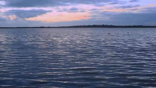 Bay waters sway peacefully; small ripples reflect raising or setting sun; water looks cool and calm.