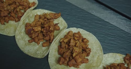 Amazing slow motion shot of a group of beef tacos in a restaurant kitchen. Typical Mexican food.