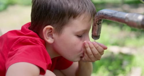 Boy Drinking Water from Outdoor Tap