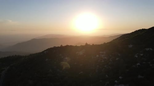Aerial drone panorama of the sun setting above the forested hills in California. Autumn season, the