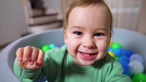 Smiling Infant Waving Hand in a Ball Pit