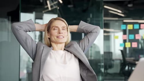 Happy businesswoman in a suit finished task on laptop sitting at workplace in business office.