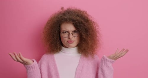 Woman Shrugs with Confused Expression on Pink Background