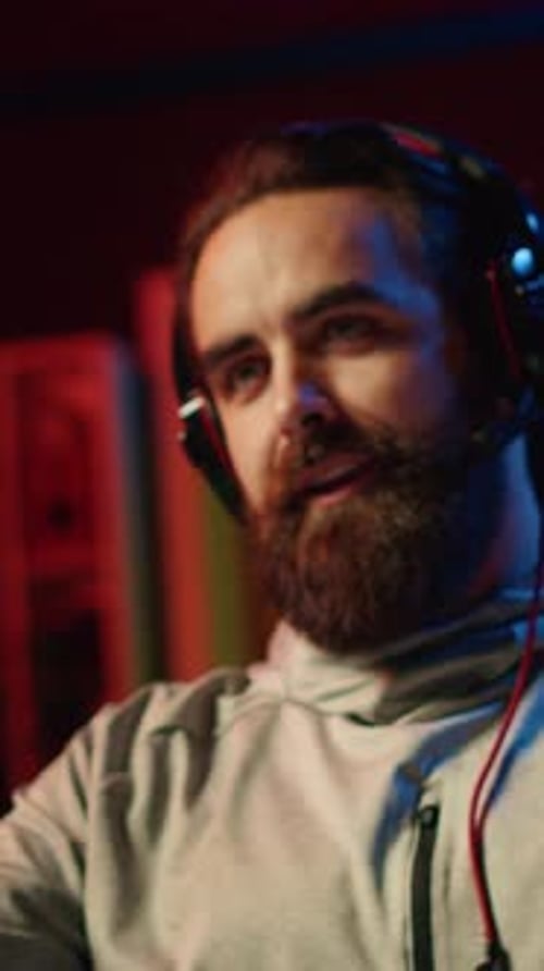 Man with Headphones Typing at Keyboard in Dark Room