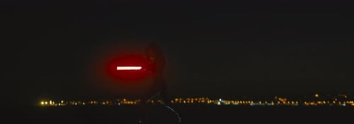 Silhouette d'un guerrier brandissant un sabre laser rouge à double lame