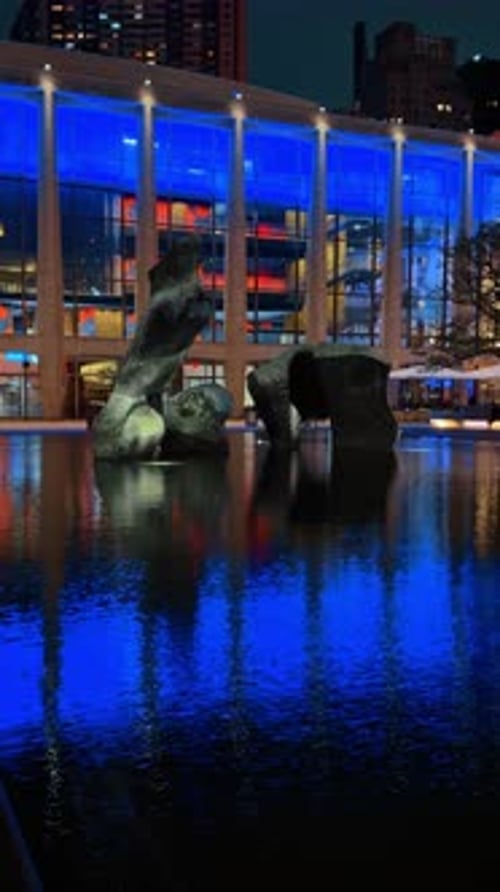 Night view of modern sculpture in illuminated pool. Abstract dark sculpture standing