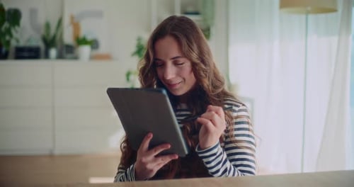 Hermosa mujer sonriente usando una tableta digital mientras está sentada en casa