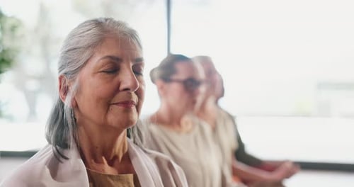 Senior Women Meditating Together Indoors in Peaceful Sunlight