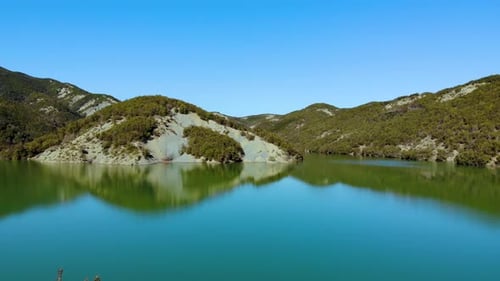 Paradise mountain lake with calm clear water surface reflecting mirror of mountains slopes with lush