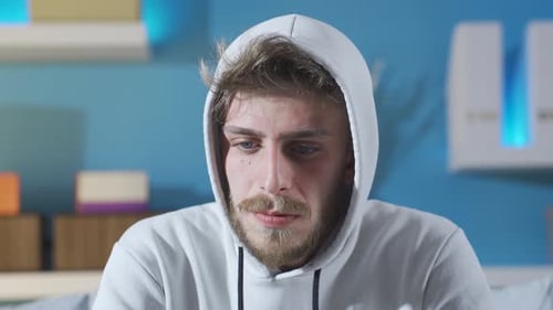 Beunruhigter depressiver junger Mann mit Schwierigkeiten beim Denken und Blick in die Kamera.