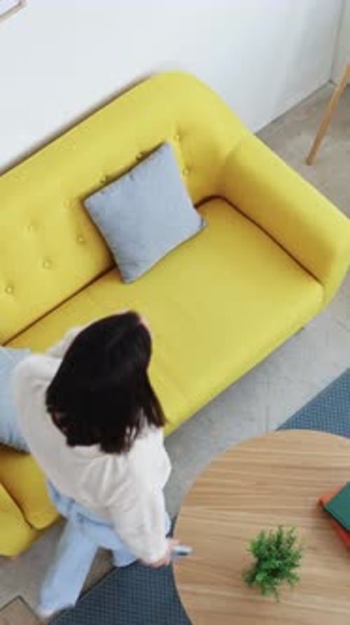 Woman Relaxing with Smartphone on Yellow Couch