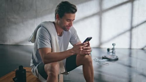 Man Using Smartphone in Gym After Workout