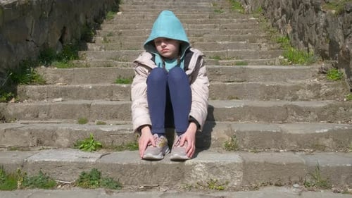 Alone child sitting on stone steps.