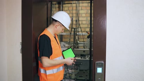 Worker Inspects Elevator With Tablet