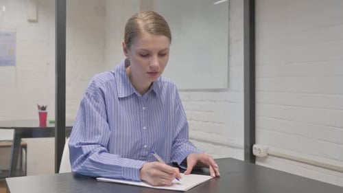 Woman Writing at Desk in Bright Office