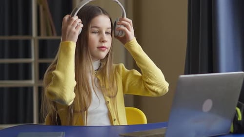 Girl Puts on Headphones to Study