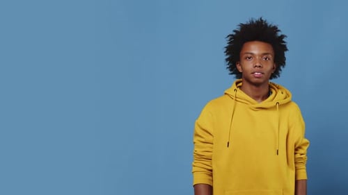 Young Adult Man Giving Thumbs Up Gesture on Blue Background