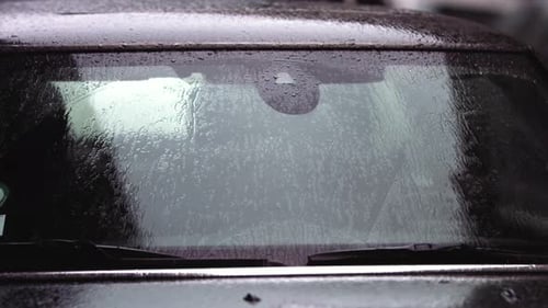 Superzeitlupenaufnahmen von Regentropfen, die auf die Windschutzscheibe eines Autos treffen.
