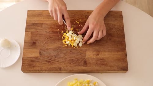 Woman Dicing Hard Boiled Egg on Cutting Board