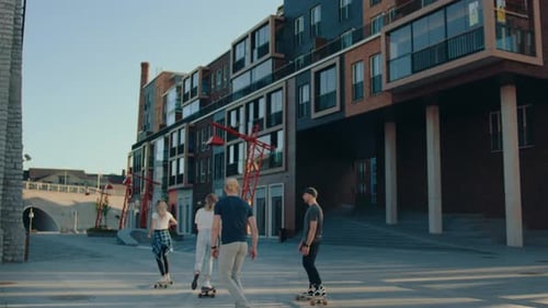 Group of Girls and Guys Riding on Skateboards Through Fashionable Hipster District. Beautiful Young