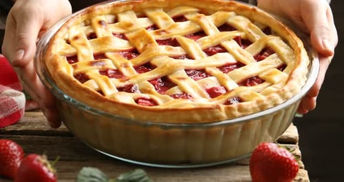 Woman putting tasty strawberry pie at wooden table, closeup