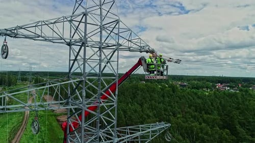 Close up shot of workers installating power line pylon using construction equipment over a newly ins