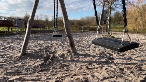 Balançoire vide se balançant doucement dans une aire de jeux pour enfants en gros plan