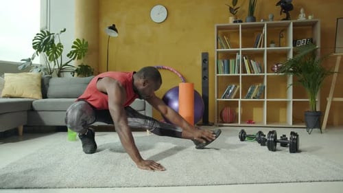 Muscular Man Stretching Leg on Carpet at Home