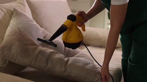 Woman Steaming Pillow on Couch with Steam Cleaner