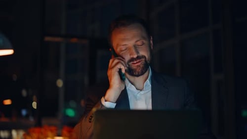 Positive Consultant Talking Cellphone Looking Laptop at Night Office Closeup