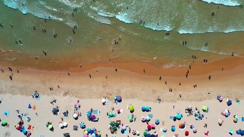 Aerial View of Bustling Beach with Colorful Umbrellas and People Enjoying Sun on Summer Day