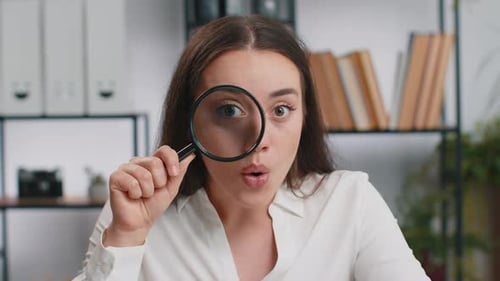 Geschäftsfrau hält Lupe in der Nähe des Gesichts und schaut mit großen gezoomten Augen suchen und analysieren
