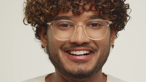 Vue de face d'un jeune homme heureux portant des lunettes Vidéo studio d'un homme souriant aux cheveux bouclés Positive