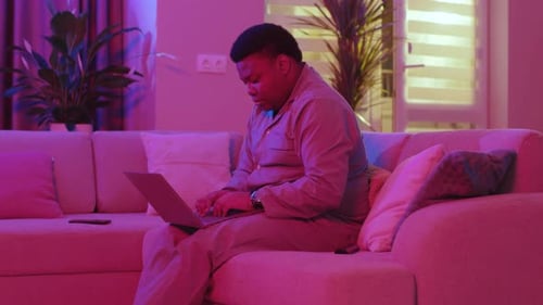 Man in pajamas working on laptop at home