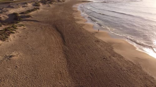 Aerial drone shot of person relaxing on sandy beach and watching waves of Ocean during bright sunny