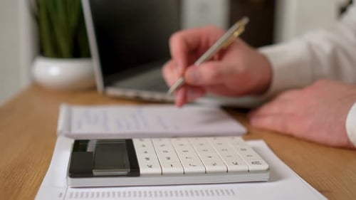 Geschäftsmann berechnet Steuern auf Taschenrechner in Nahaufnahme und schreibt Notizen mit Stift in Notizbuch arbeitet an