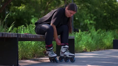 young hipster girl puts on roller skates in skate park before starting skating street extreme sport