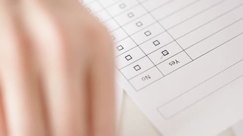 Hand filling out a survey form with pen