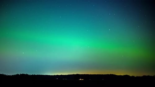 Time-Lapse of clouds moving over vibrant aurora borealis and stars on a night sky