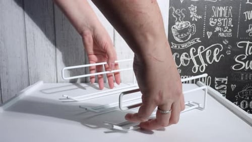 Une femme sort un porte-lunettes suspendu pour la cuisine. Fait un examen des achats.