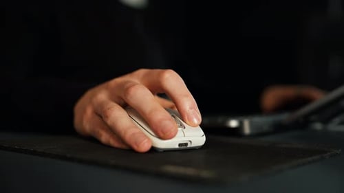 Person using computer mouse in office or home, focused at work.