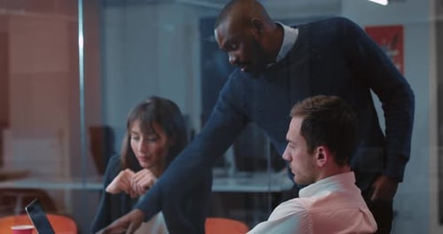 Three Young People Looking at Laptop and Discussing Something in Beautiful Modern Office on