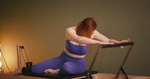 Woman Stretching on Pilates Reformer Machine Indoors