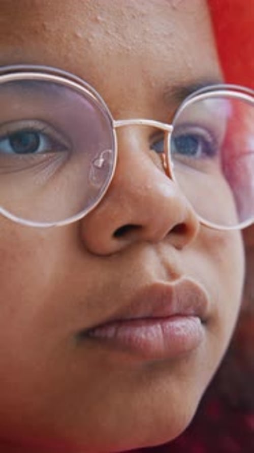 Young Girl Focused on Reading a Book While Wearing Glasses Indoors