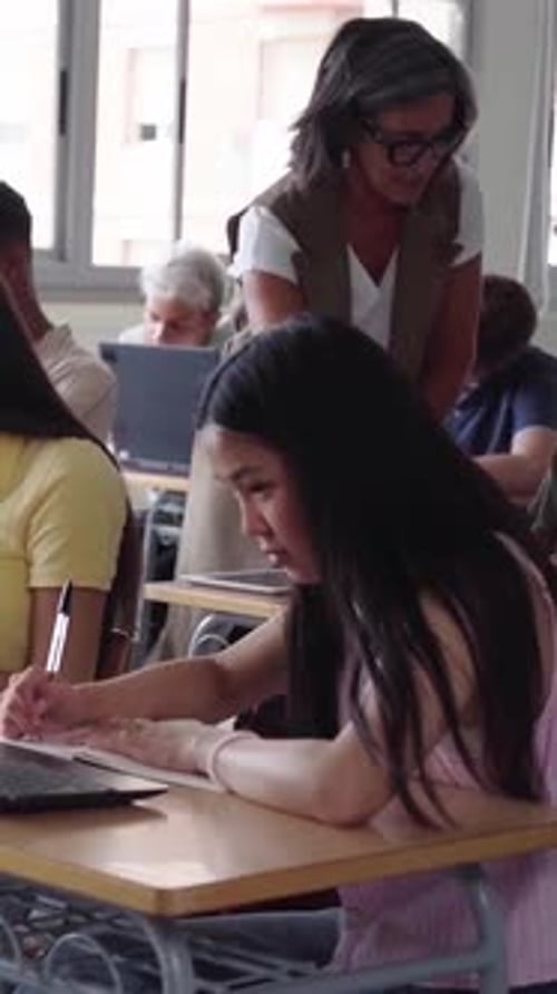 High School Teacher Helping Student During Exam in Classroom