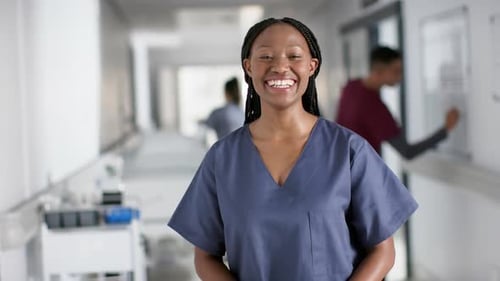 Portrait of happy african american female doctor wearing scrubs in hospital, slow motion
