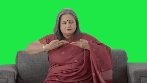 Relaxed Indian old woman doing breathe in breathe out exercise Green screen