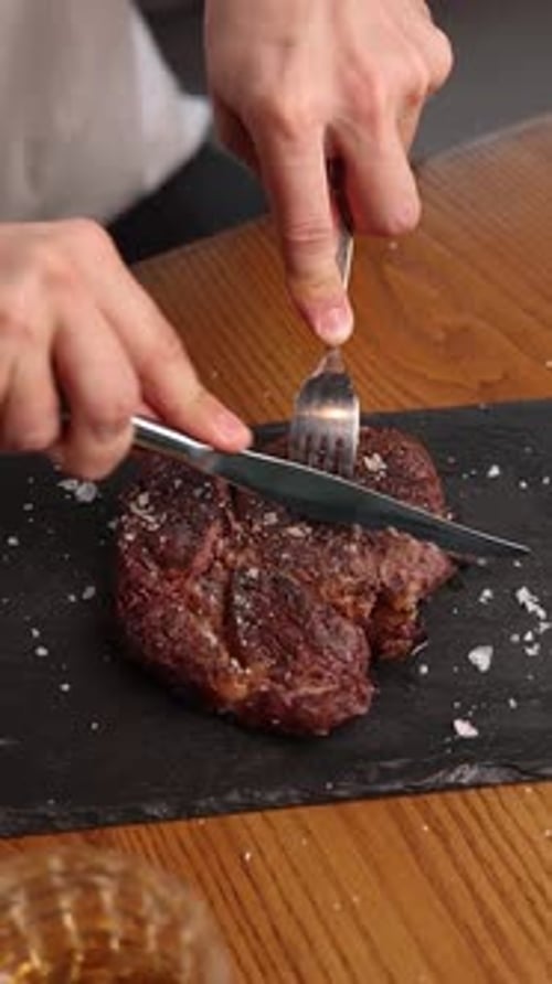 a man eats a steak in a restaurant. Only hands