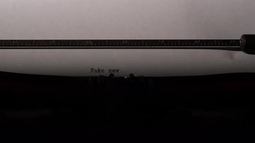 Vintage Typewriter Typing the Words Fake News on a Sheet of White Paper Illustrating Concepts of
