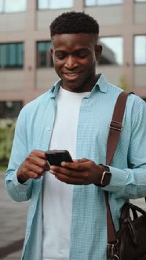 Smiling man using smartphone device outdoors